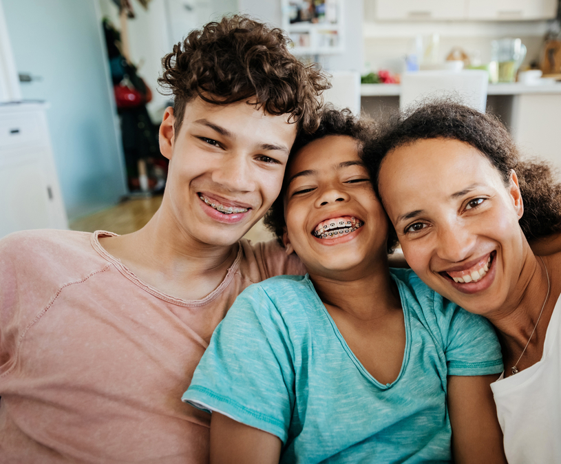 Moeder met twee kinderen maakt een selfie, ze lachen en kijken in de camera