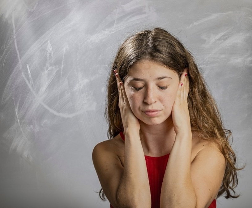 meisje houdt haar handen over haar oren en haar ogen dicht